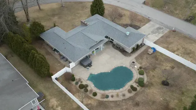 Aerial view of a house with a fenced backyard and a turquoise swimming pool