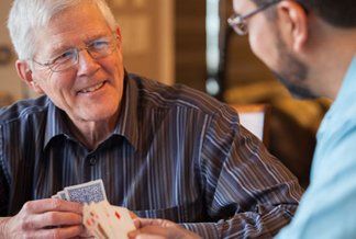 Elderly playing cards with a care giver