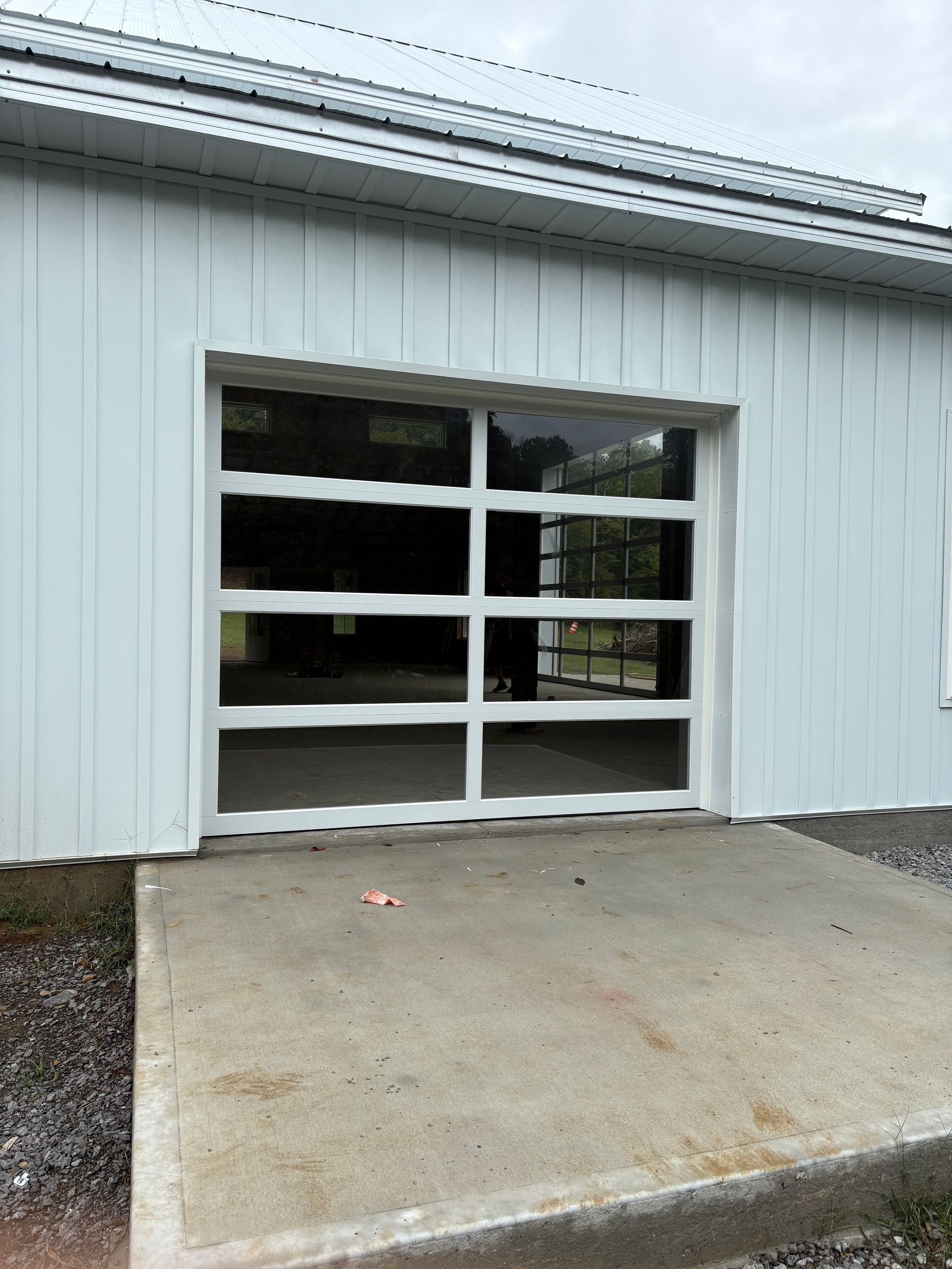 White building with a glass garage door and a concrete ramp leading to it.
