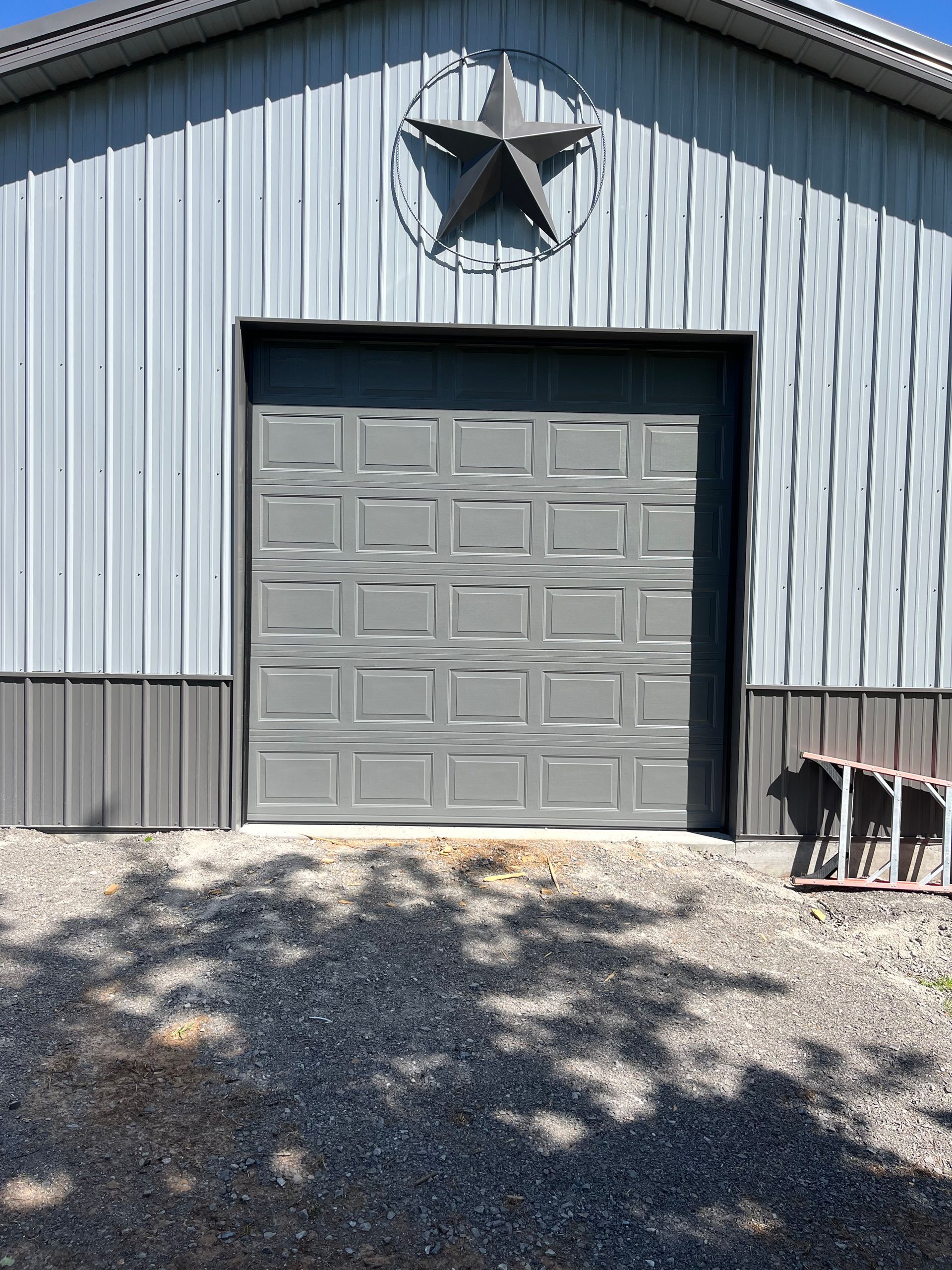 Gray metal garage door in a gray building with a star-shaped decoration.