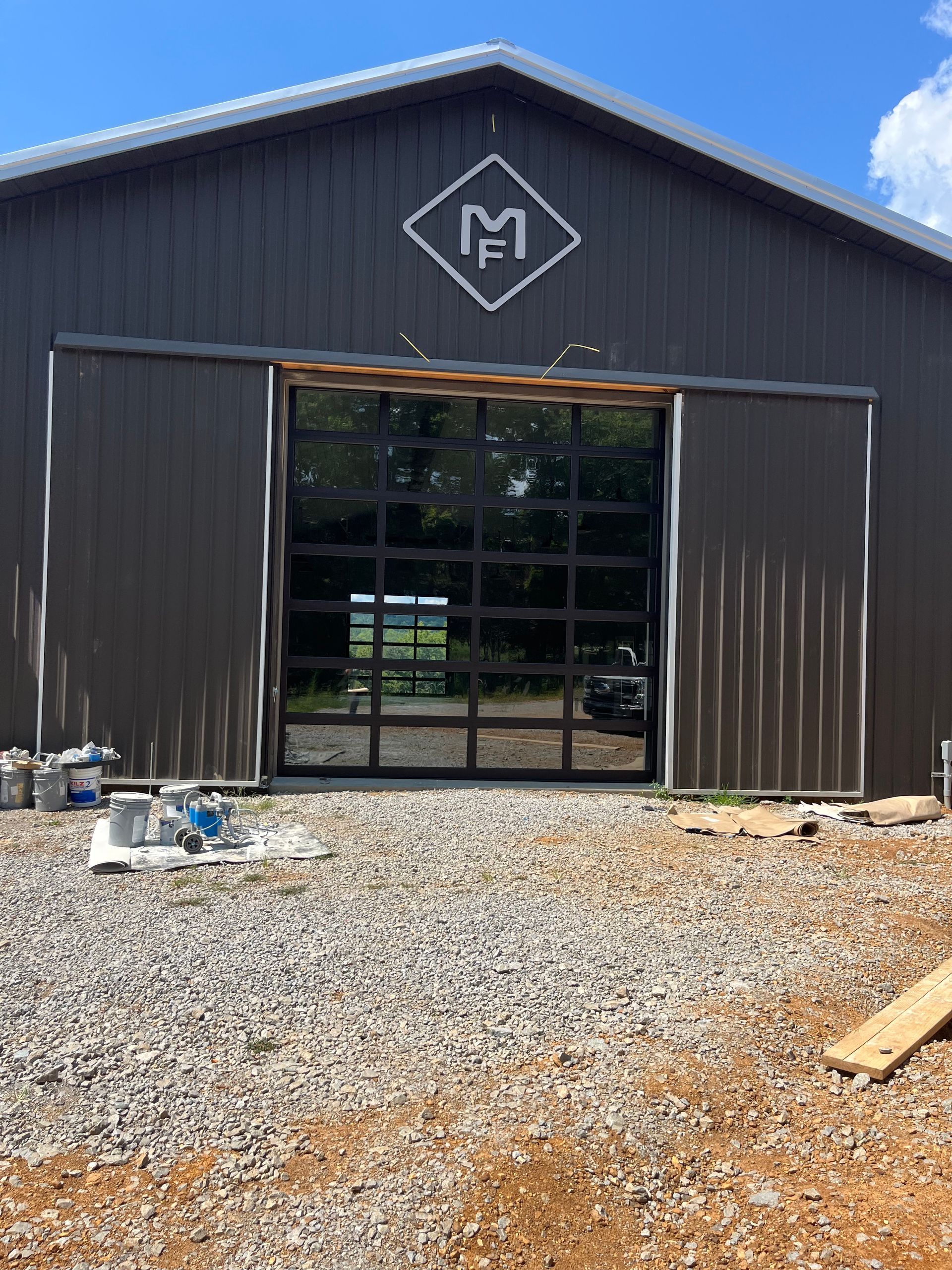 Exterior of a brown metal barn with a large glass door and an 