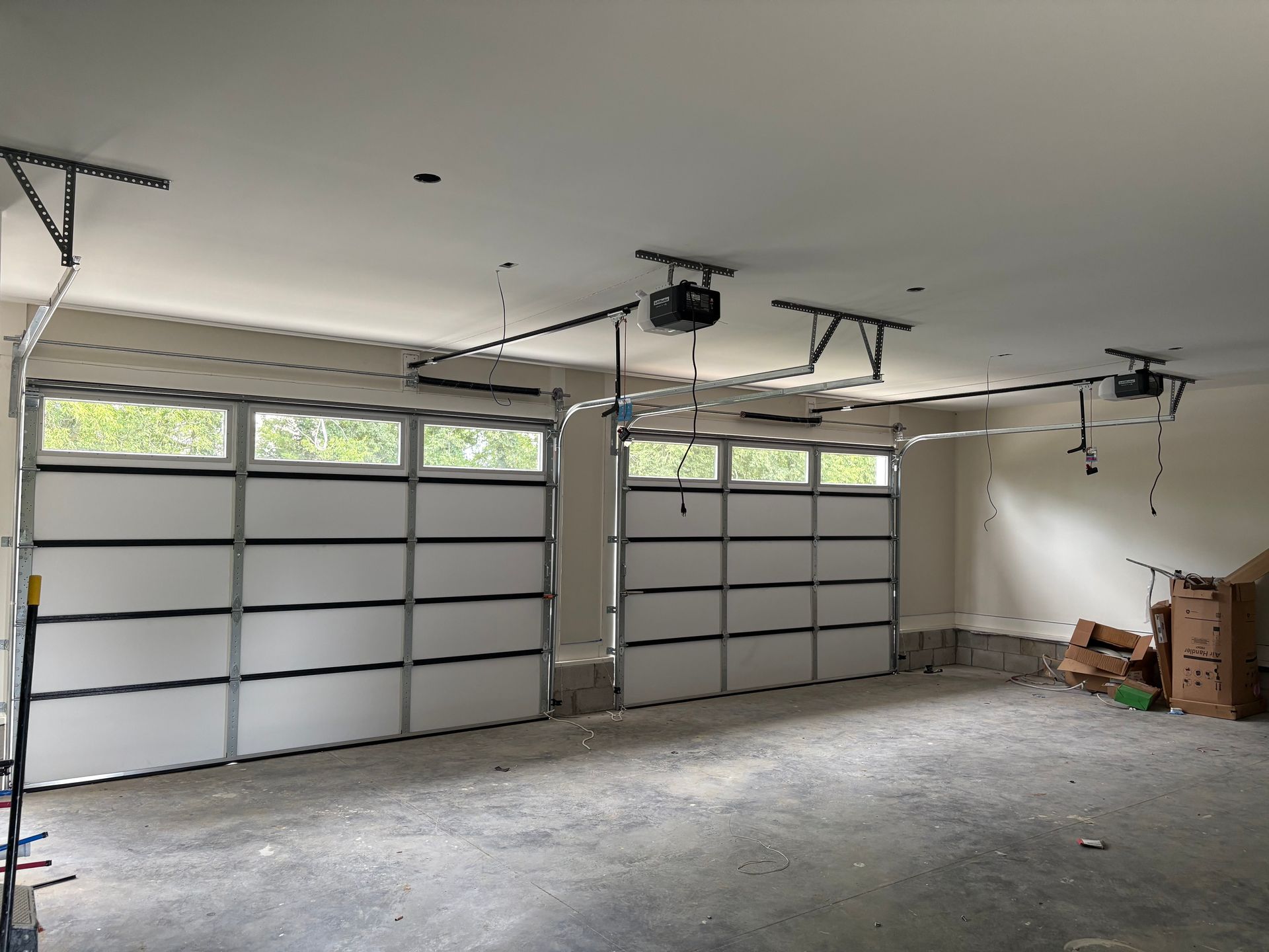 Garage interior with two white garage doors and overhead openers.