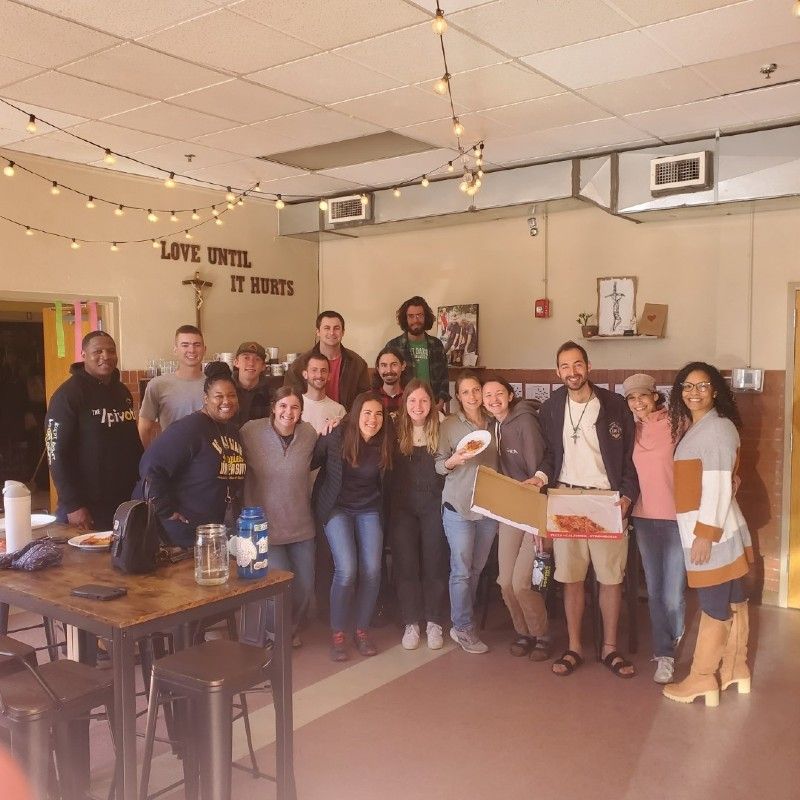 A group of people posing for a picture in front of a sign that says love until it hurts