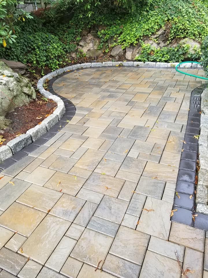 Paver patio with stone border, curved pathway leading to a garden.