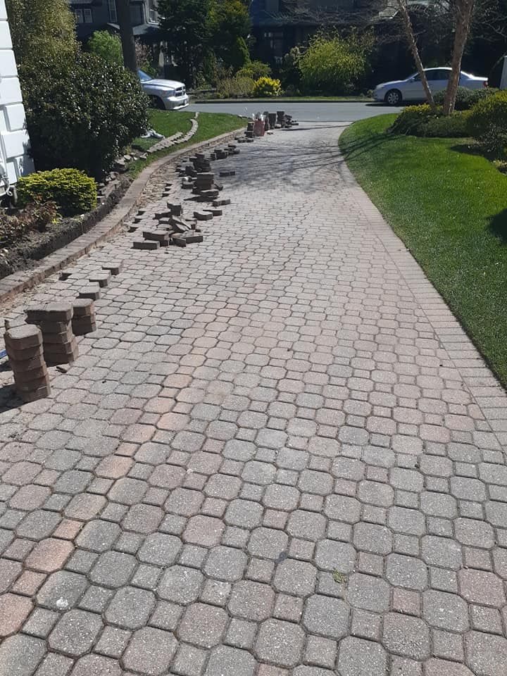 Driveway with pavers being repaired; bricks stacked along the edge.