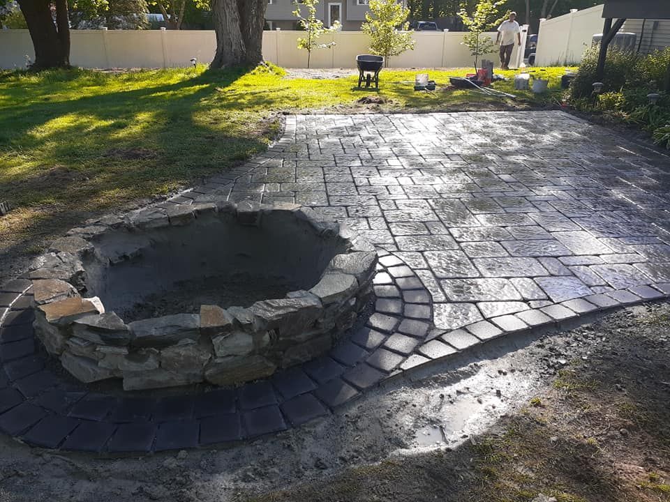 Stone patio with fire pit under construction.