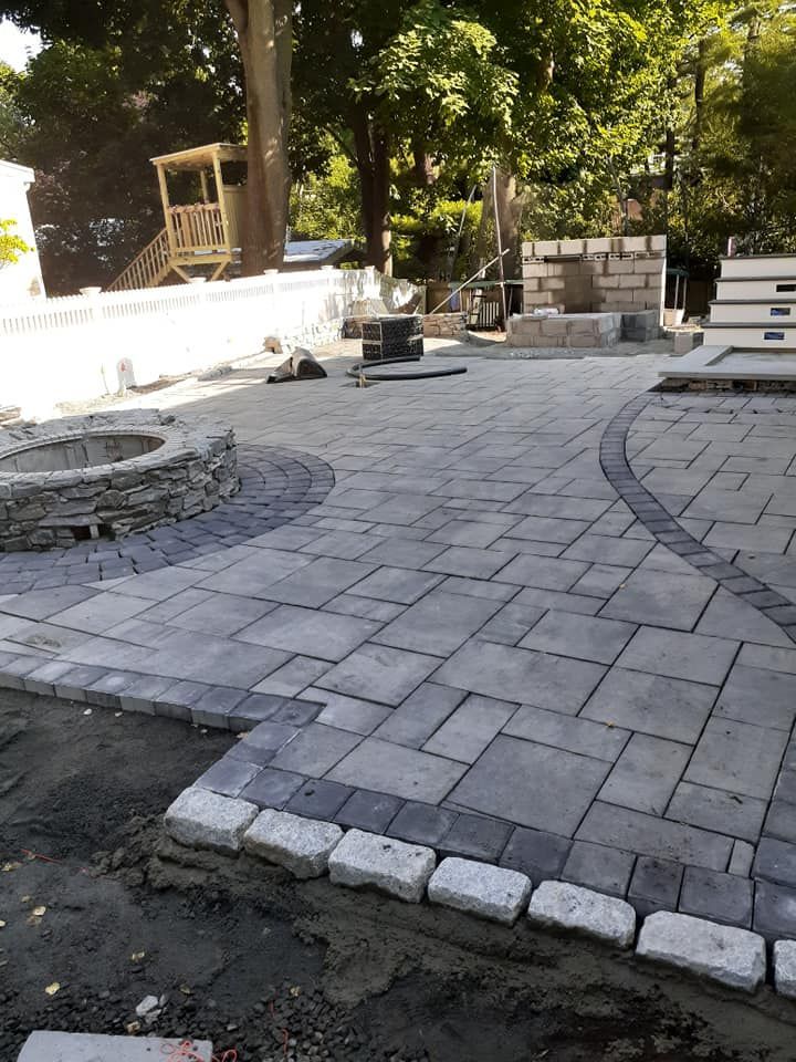 Stone patio construction with fire pit and bordering pavers.