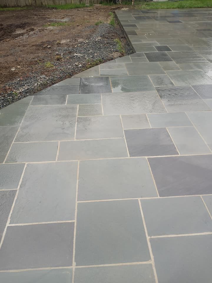 Stone patio with various gray rectangular and square tiles.