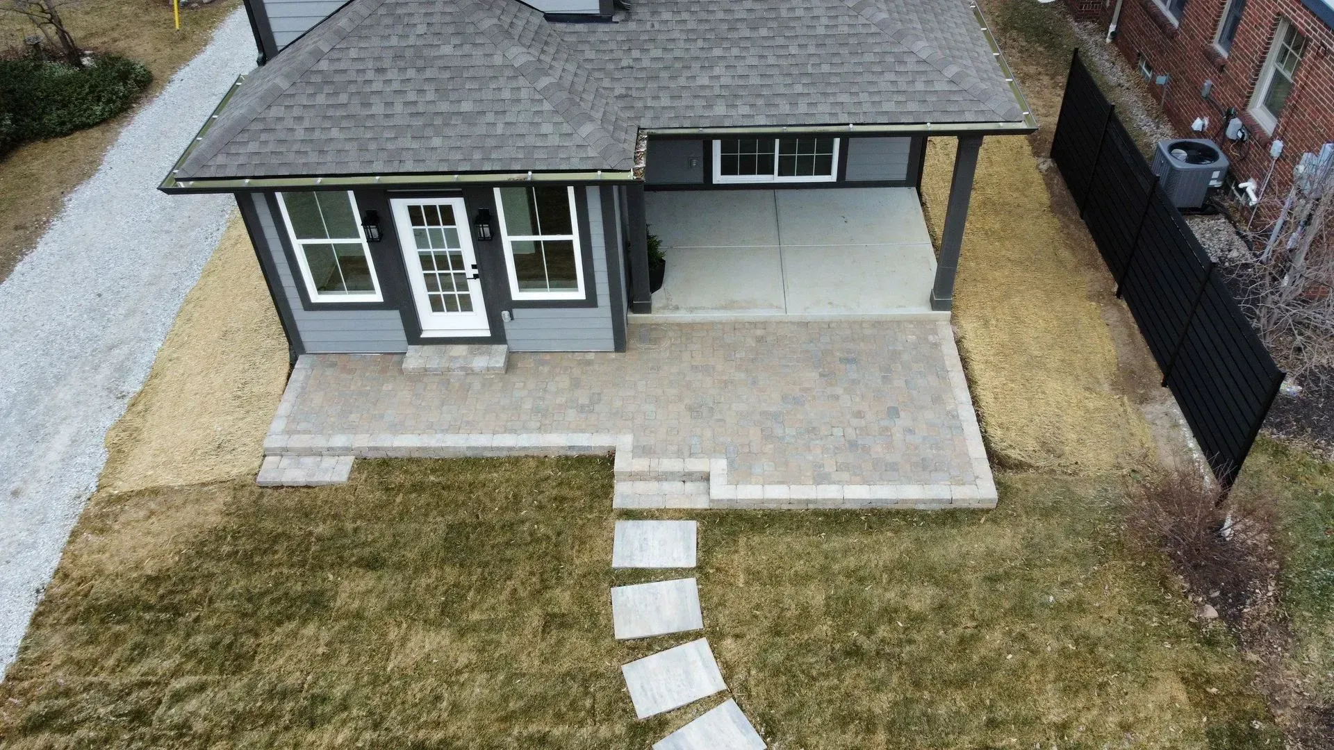 Aerial view of a house with a front porch, lawn, and stone stepping path leading to the entrance.