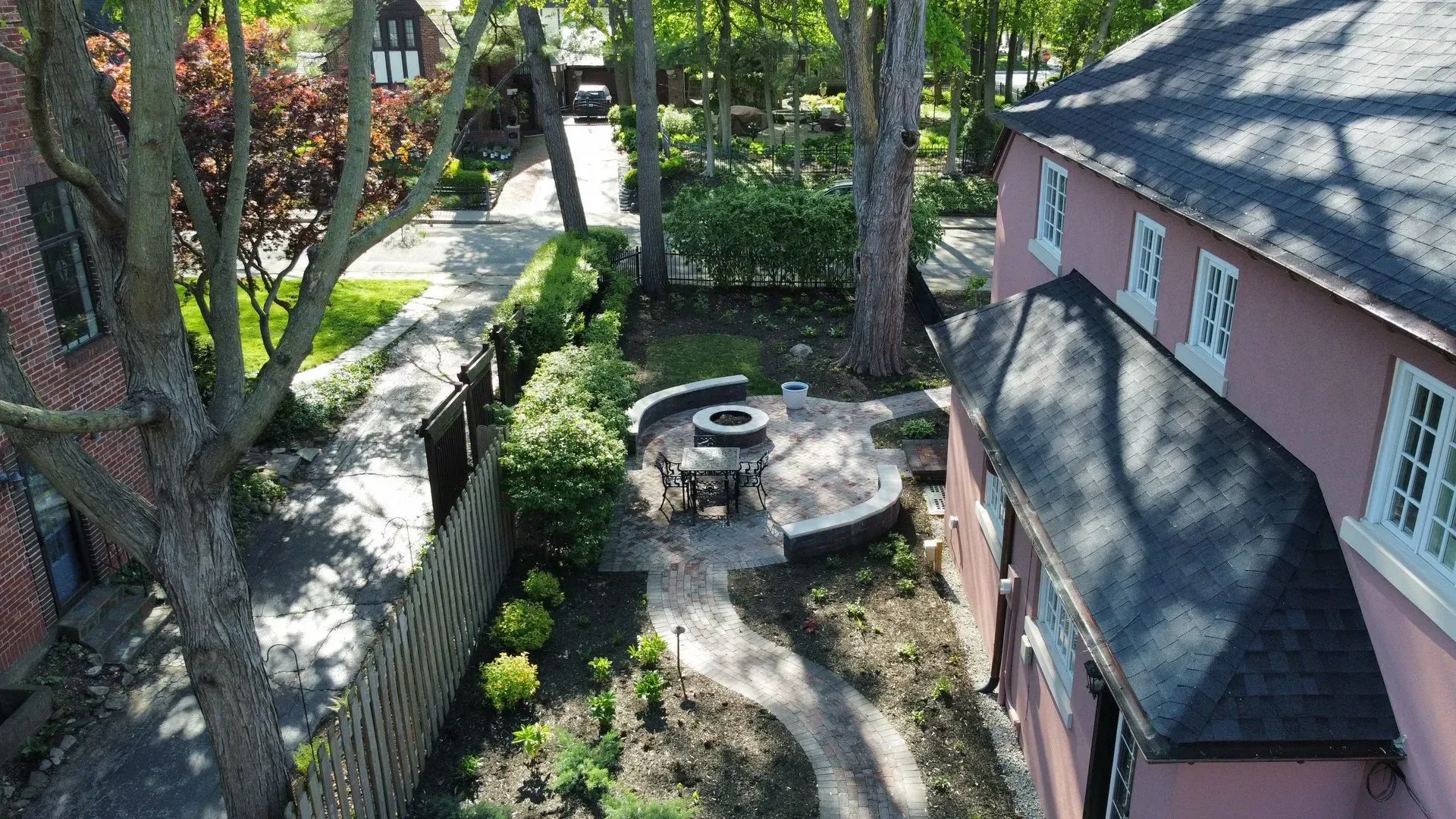 Courtyard garden with a small circular fountain, trees, hedges, and pink brick buildings.