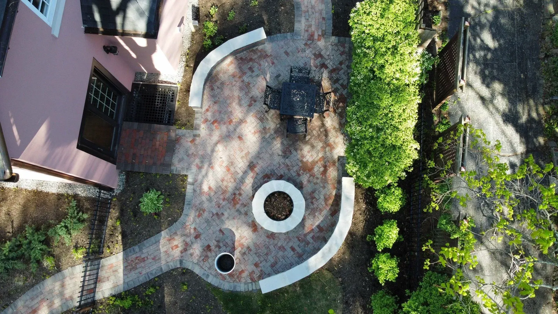 Aerial view of a circular patio with white curved benches, trees, and a building beside it.