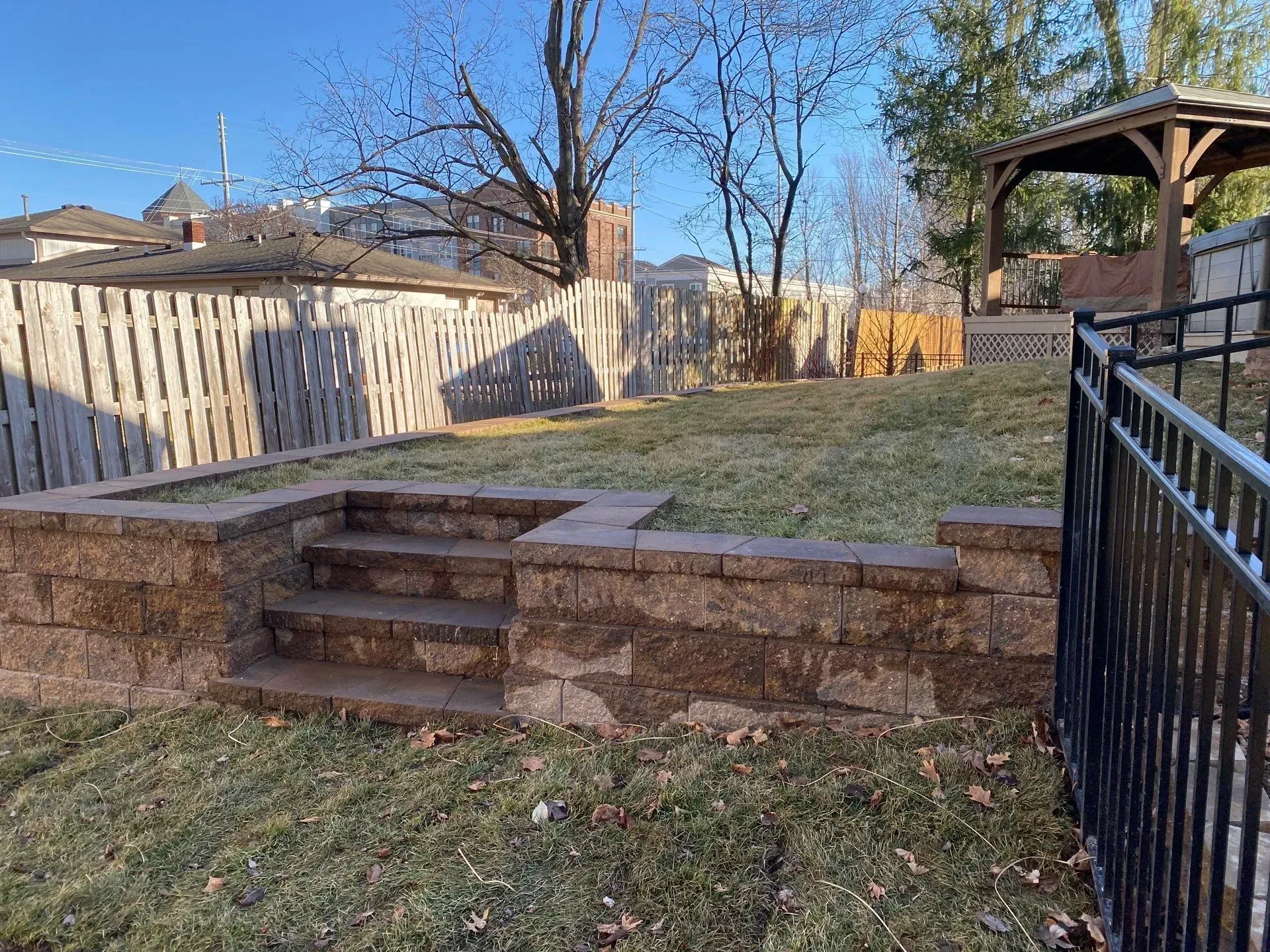 Backyard with stone steps, fenced lawn, and a covered gazebo on the right