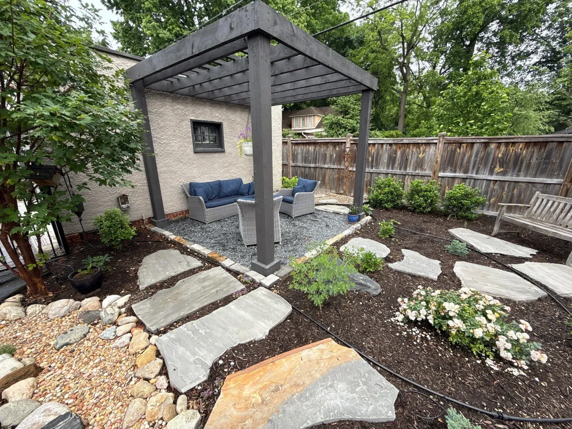 Backyard patio with gazebo, stone path, lounge chairs, and landscaped garden beds