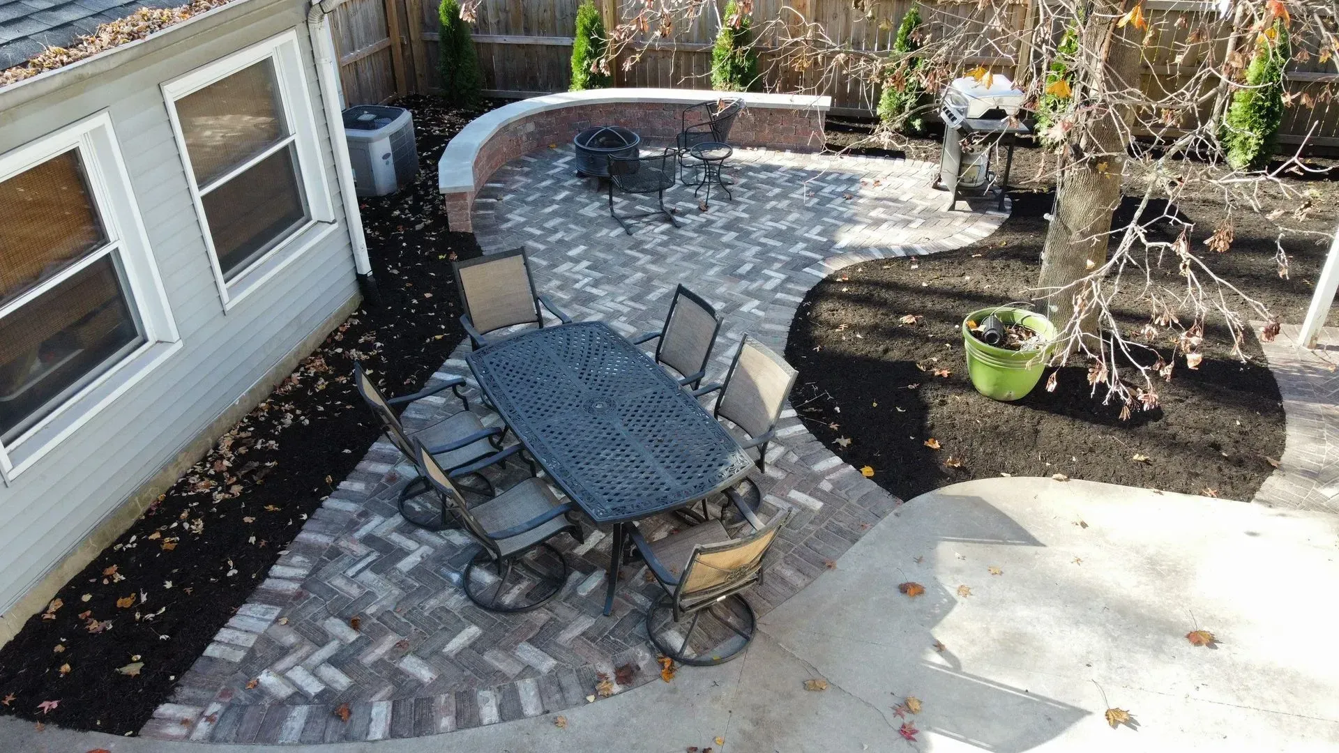 Backyard patio with a black table and chairs on a brick-and-stone patio beside a house