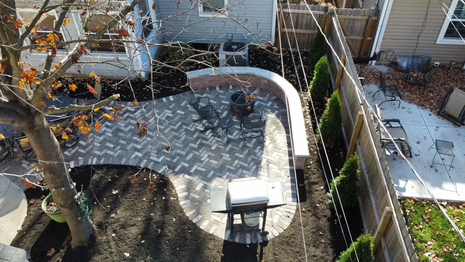 Backyard deck with gray diamond-plate surface, curved white railing, and house walls in bright sunlight