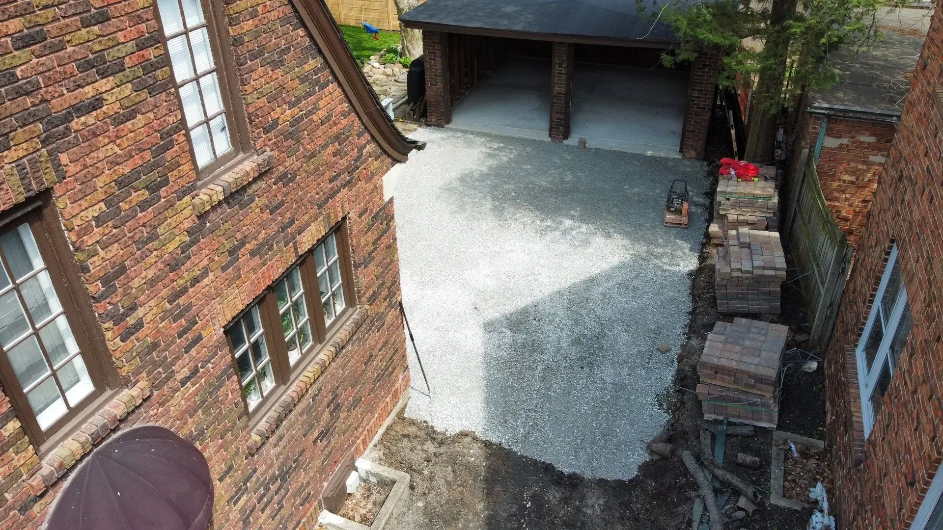 Narrow brick courtyard with gravel ground, brick buildings, and a covered doorway.