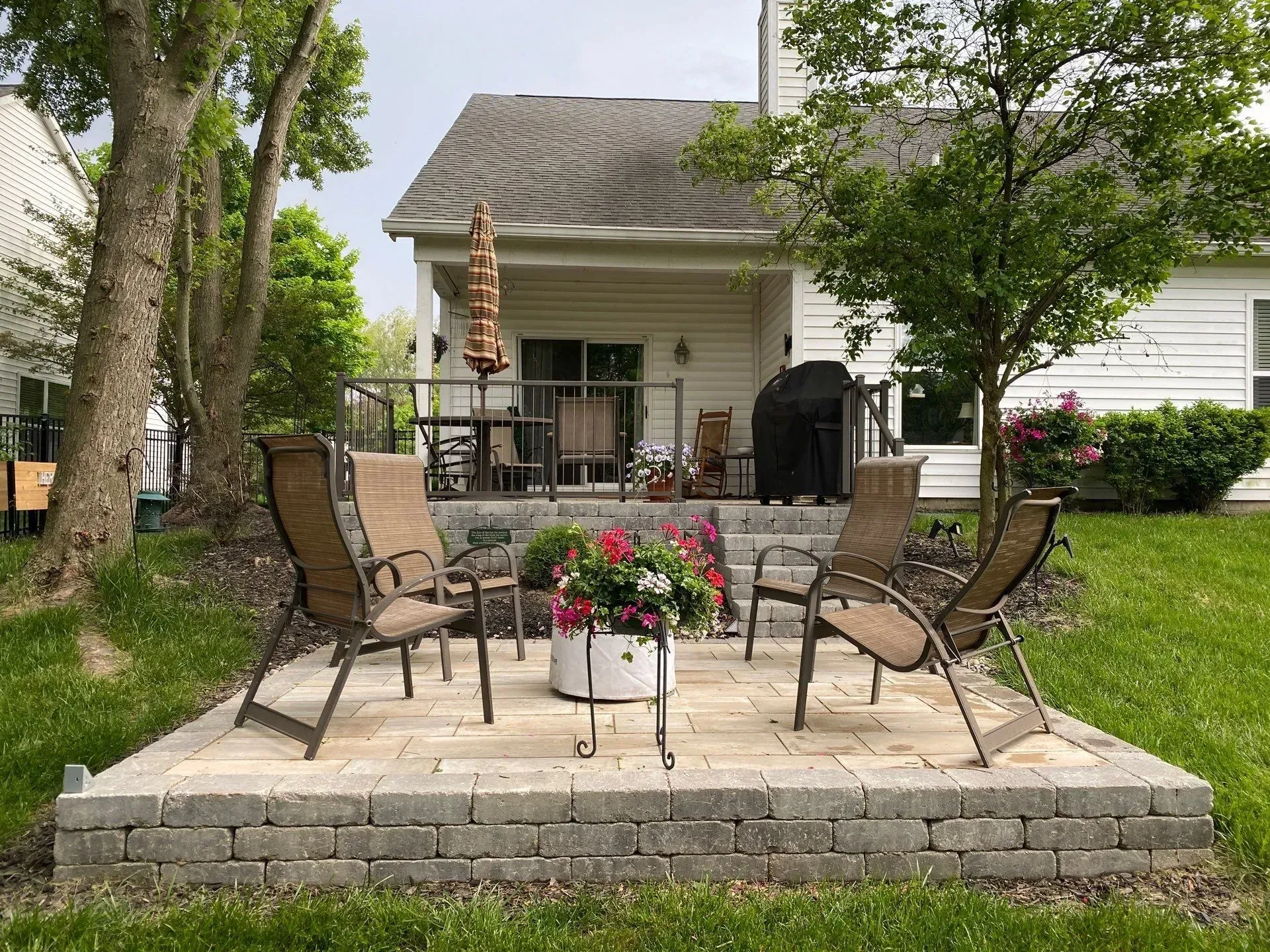 Patio with wicker chairs and flower planter on a stone terrace in a backyard garden