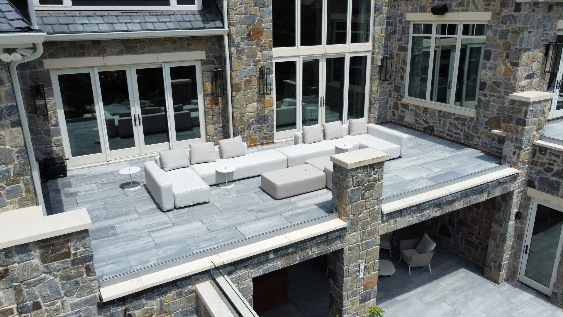 Stone patio with white outdoor sofas overlooking a modern house exterior