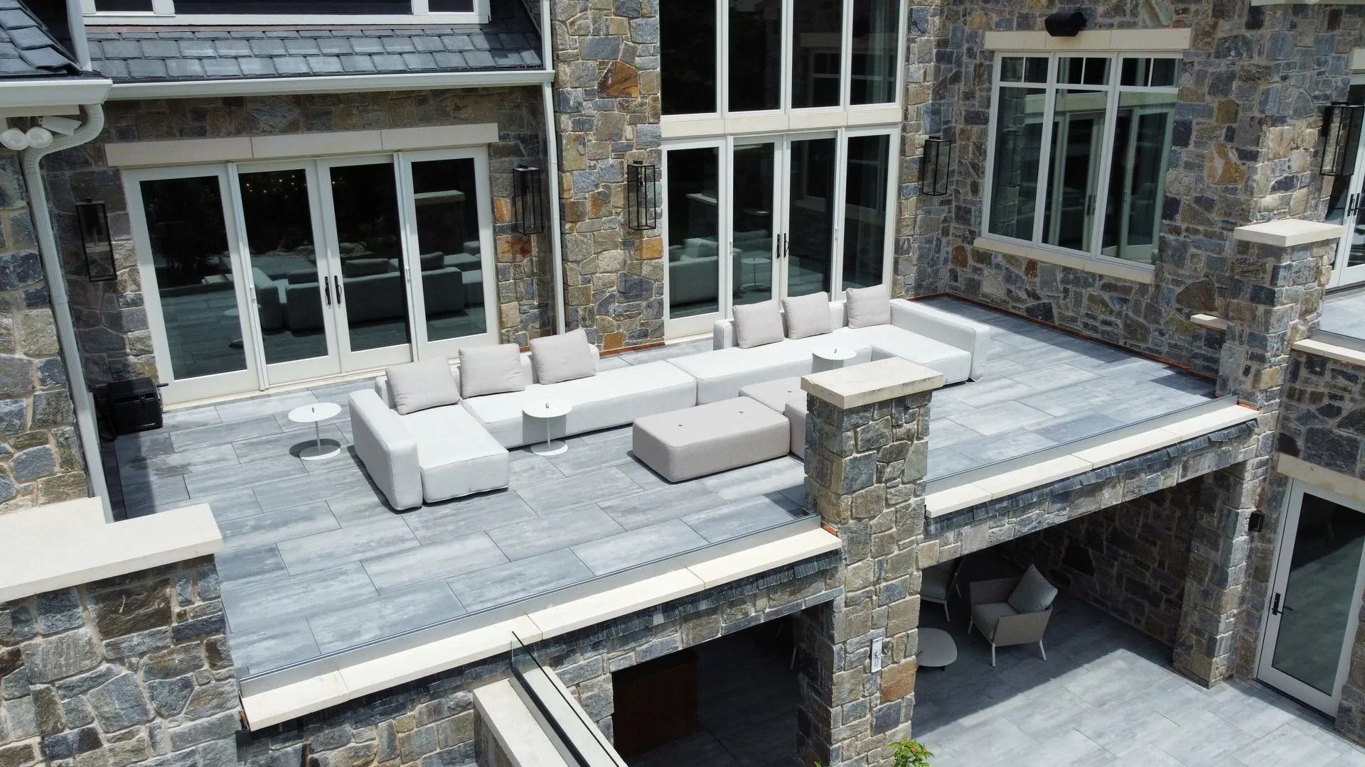 Stone patio with outdoor sectional seating on a modern house terrace overlooking a lower level