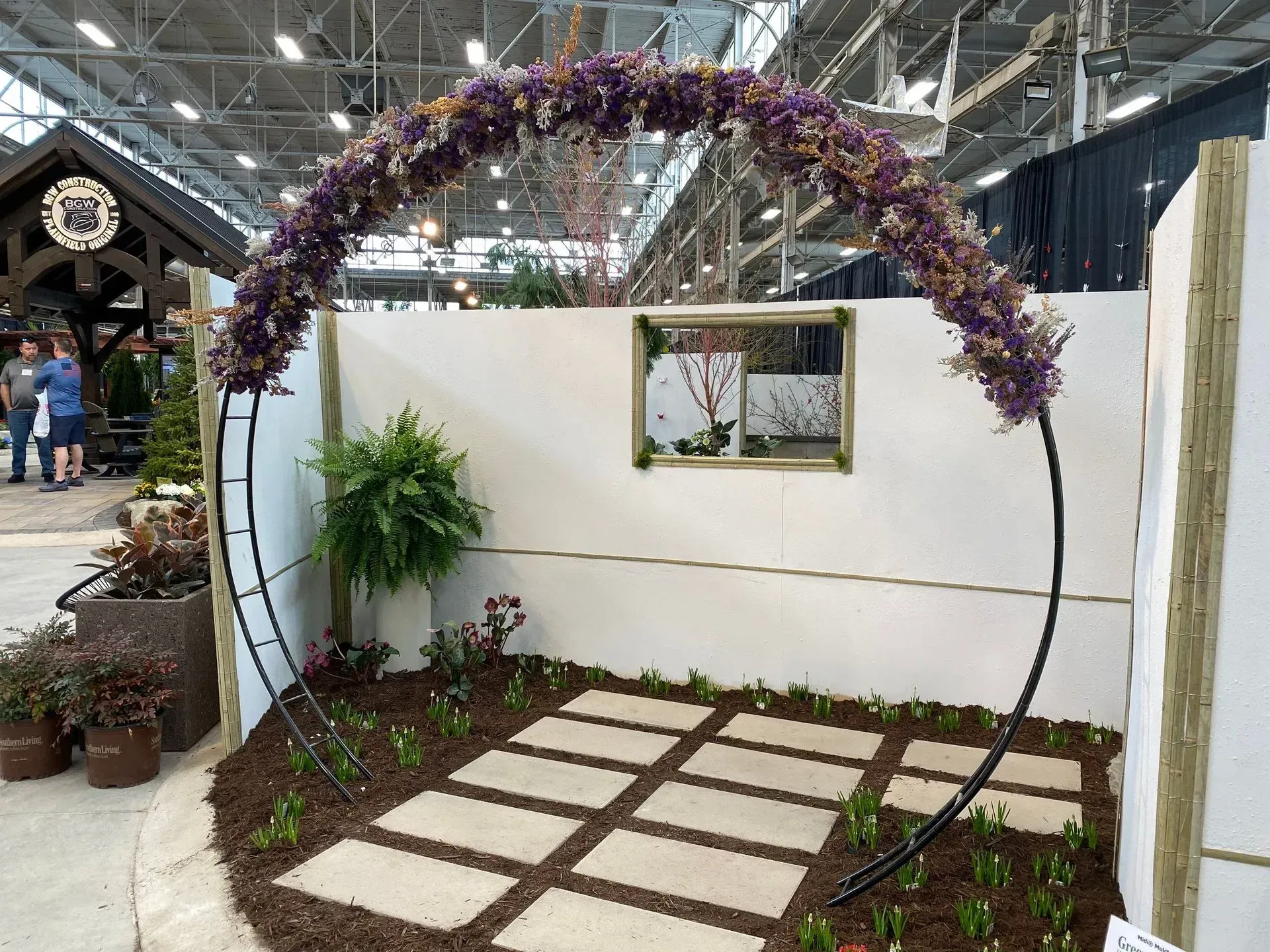Floral arch over a tiled garden display with white walls and potted plants indoors