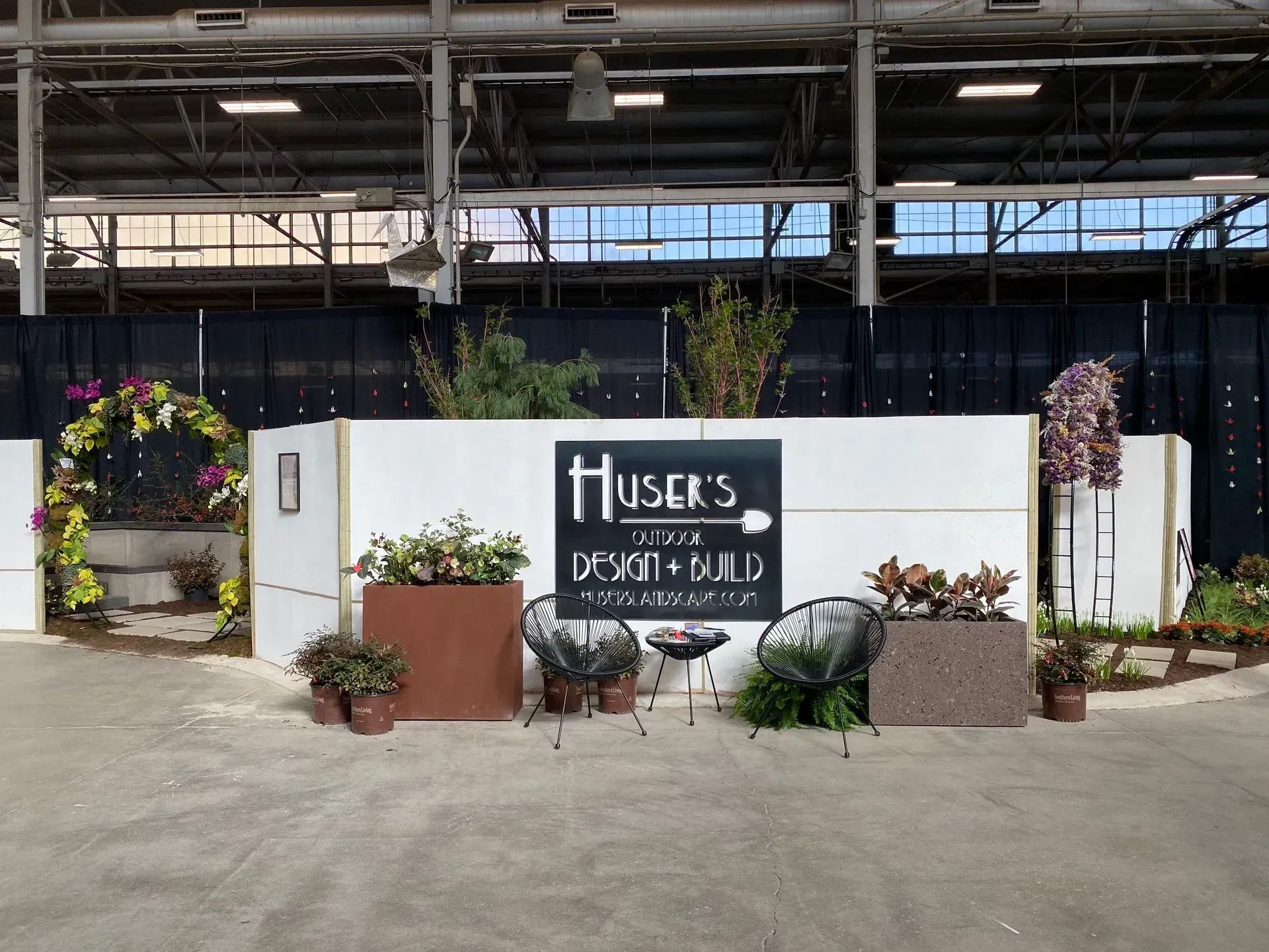 White flower shop sign with potted plants and colorful floral displays at an indoor market entrance