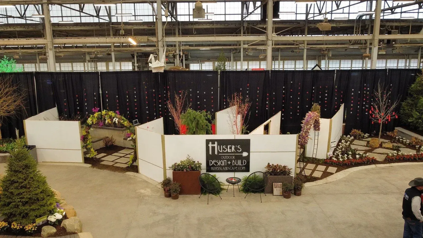 Decorated indoor memorial display with flowers, lights, and a central sign under a large structure
