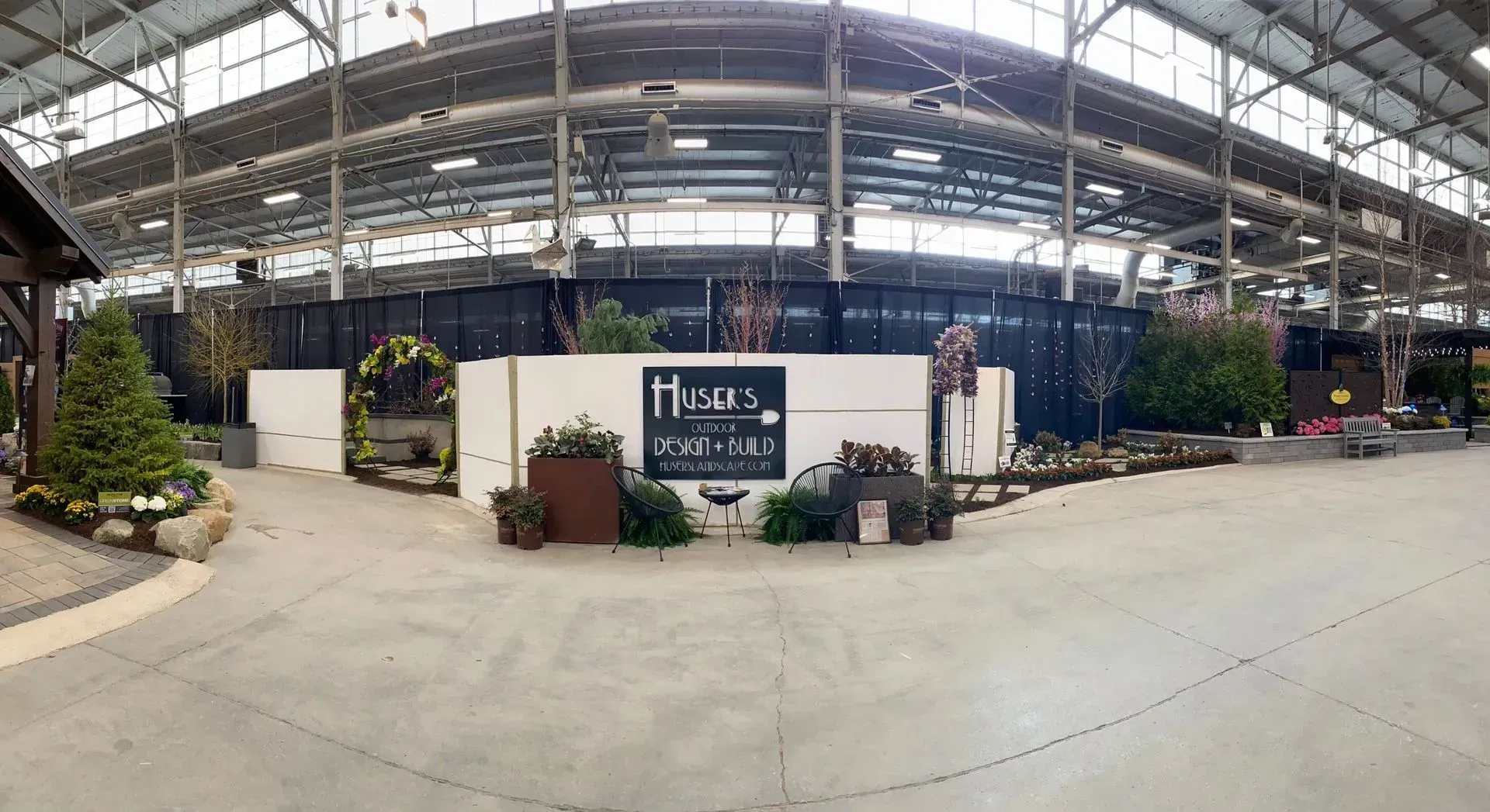Indoor market with greenhouse plants, flower displays, and a sign reading “Tropical…”