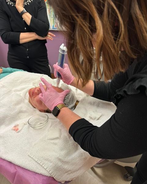 A woman wearing pink gloves is working on a patient 's face