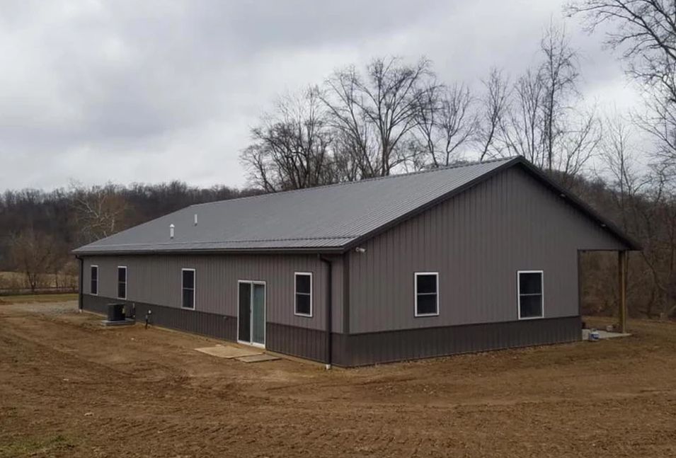 Gray metal building with a dark gray base and roof, windows, and a porch.
