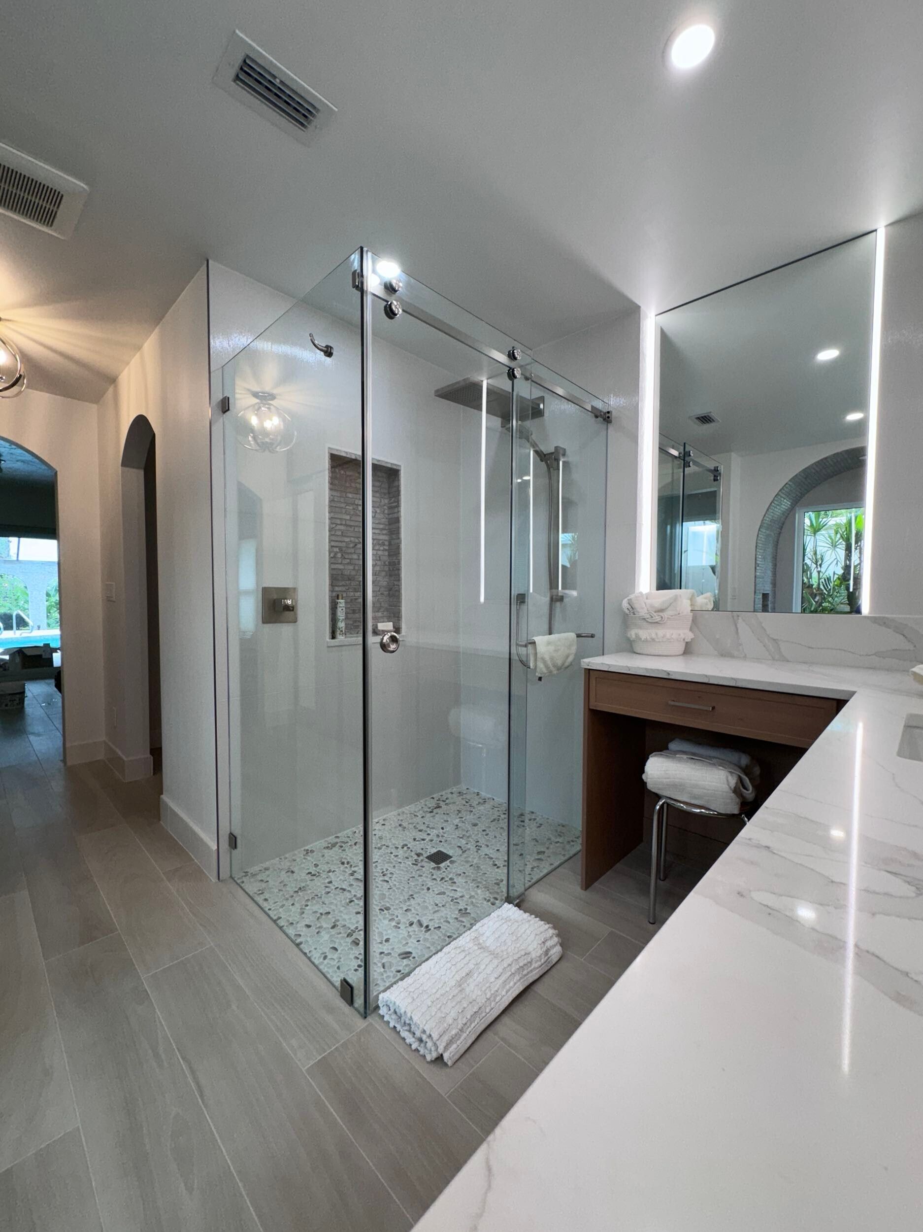 A bathroom with a walk-in shower, sink, and mirror.