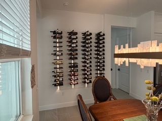 A dining room with a table and chairs, and a wine rack on the wall.