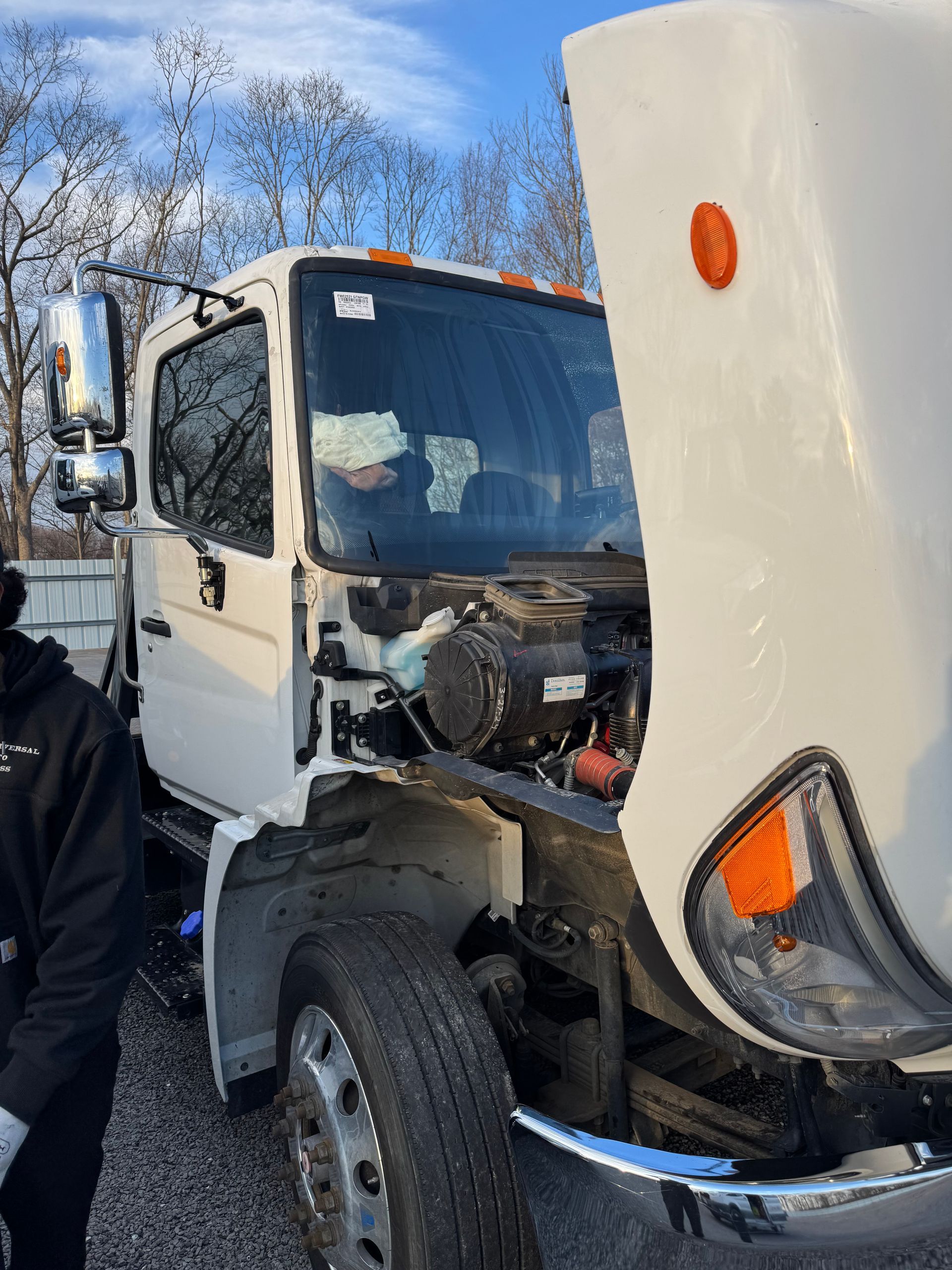 White truck with hood open, parked outdoors on a sunny day.
