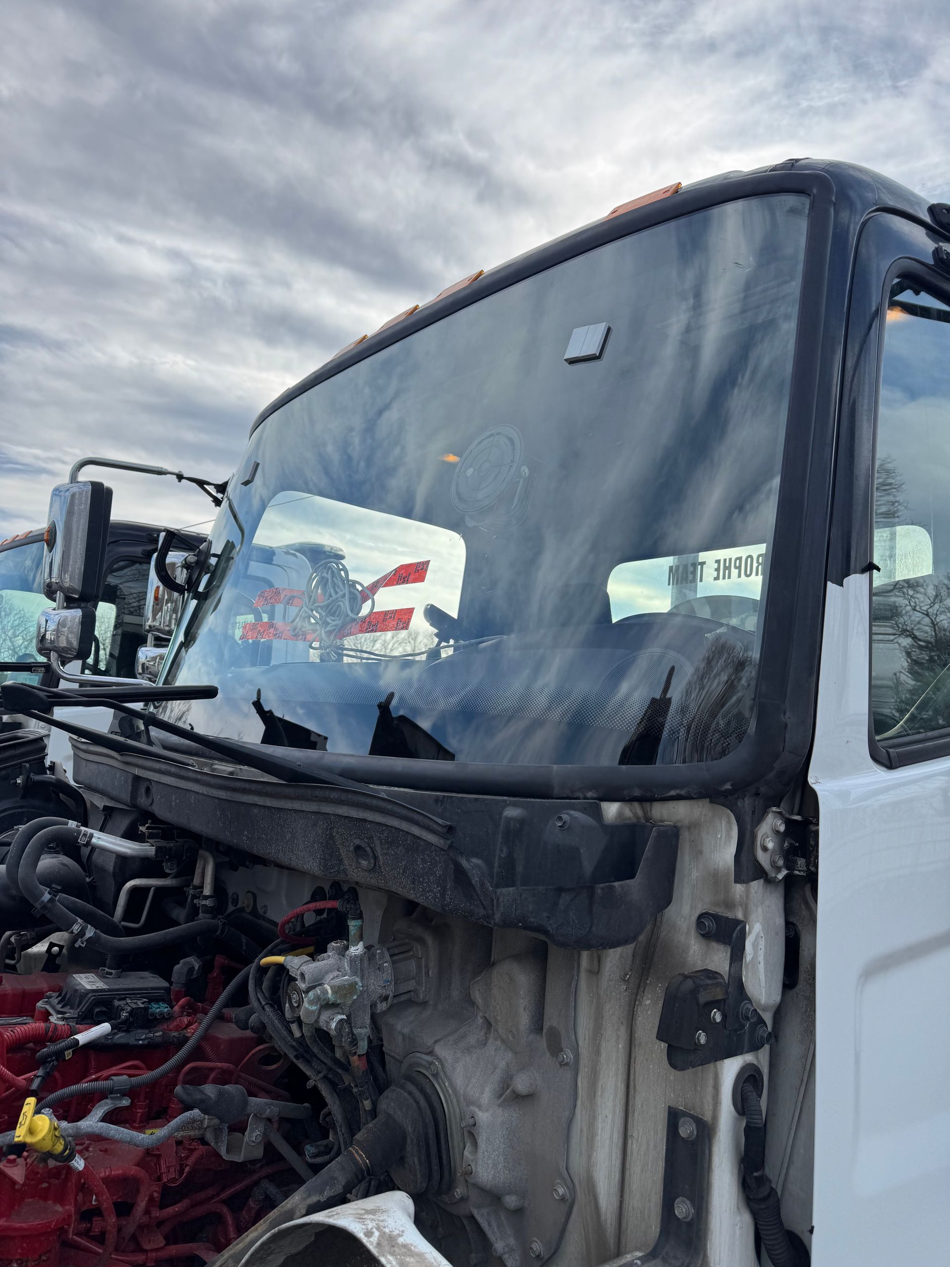 Cab of a white truck with windshield, weathered, in an outdoor setting.