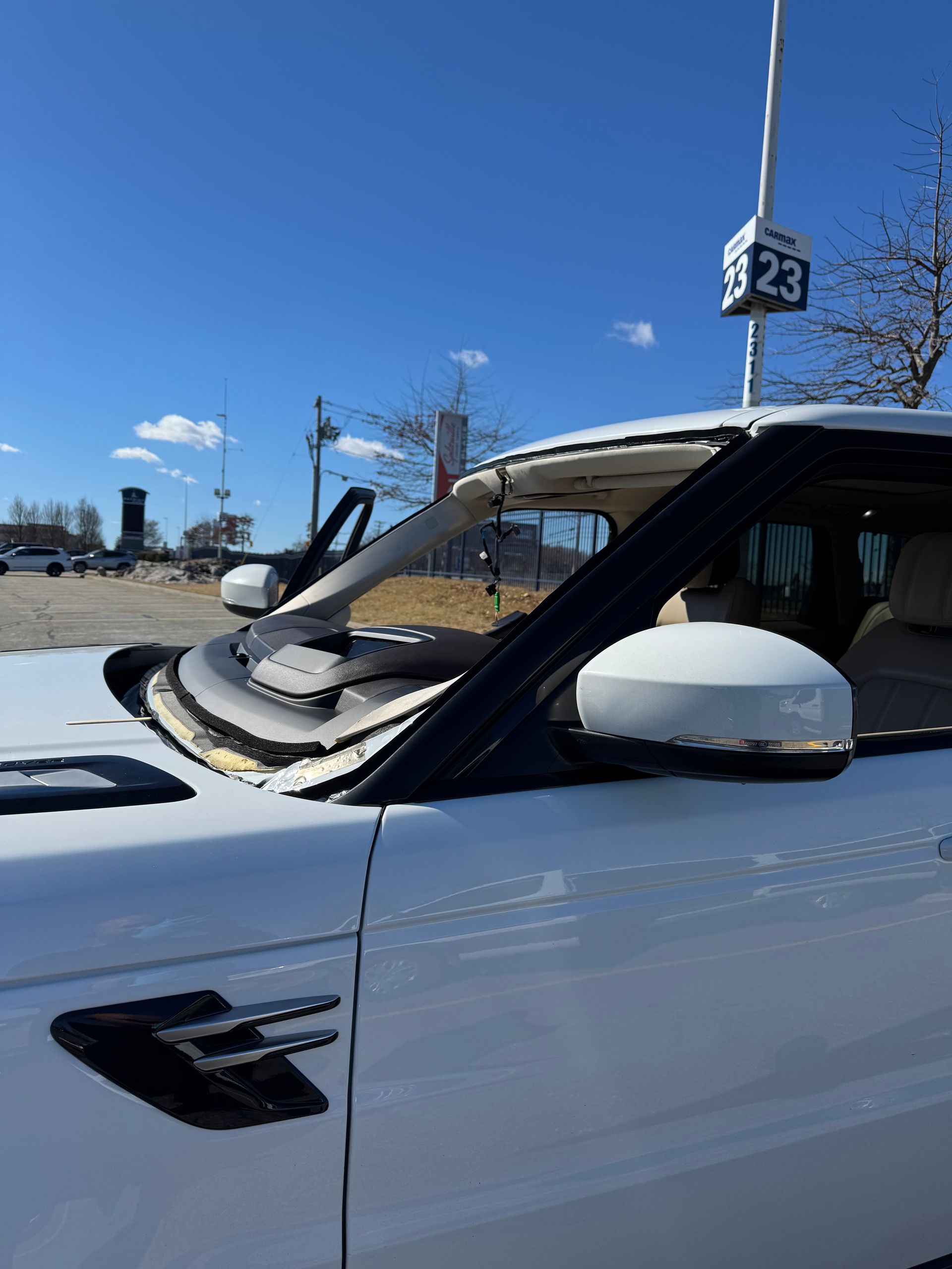 White Range Rover with a damaged windshield, parked outdoors on a sunny day.