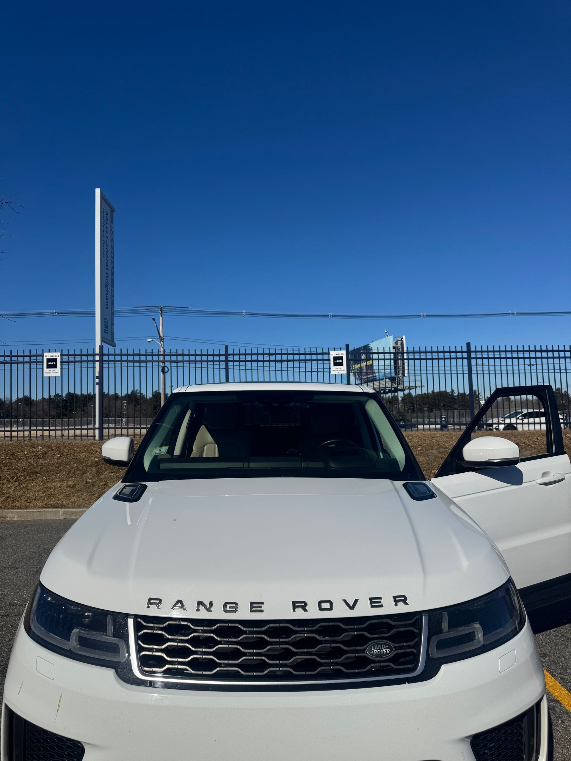 White Range Rover parked outside on a sunny day with door open.