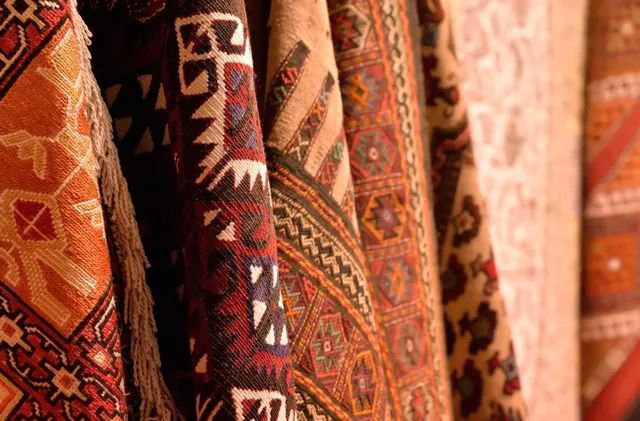 a bunch of colorful rugs are hanging on a wall