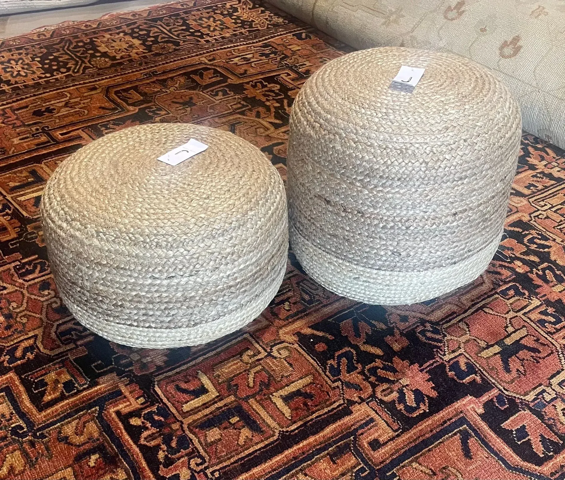 Two ottomans are sitting on top of a rug.