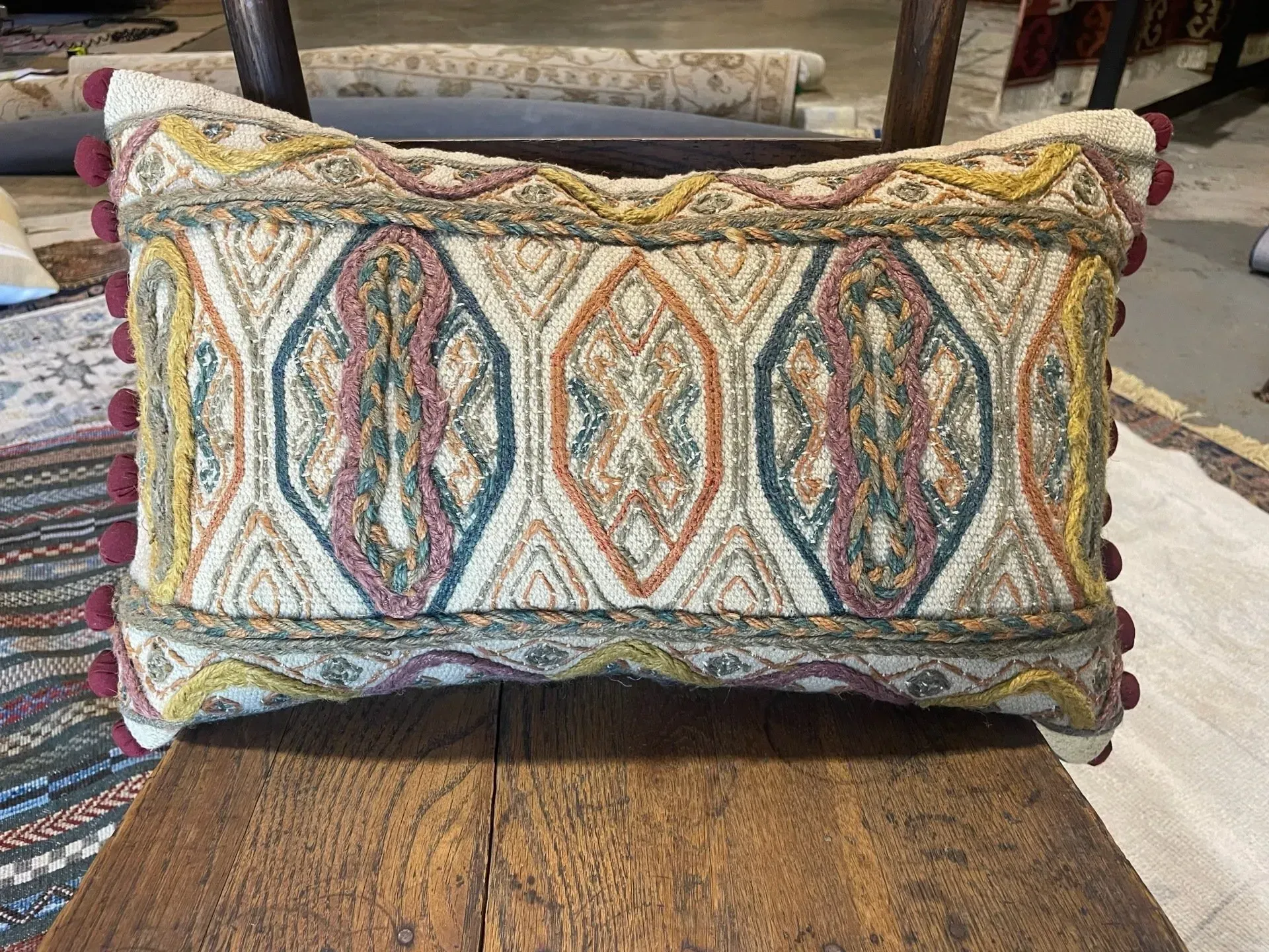 A colorful pillow is sitting on a wooden table.