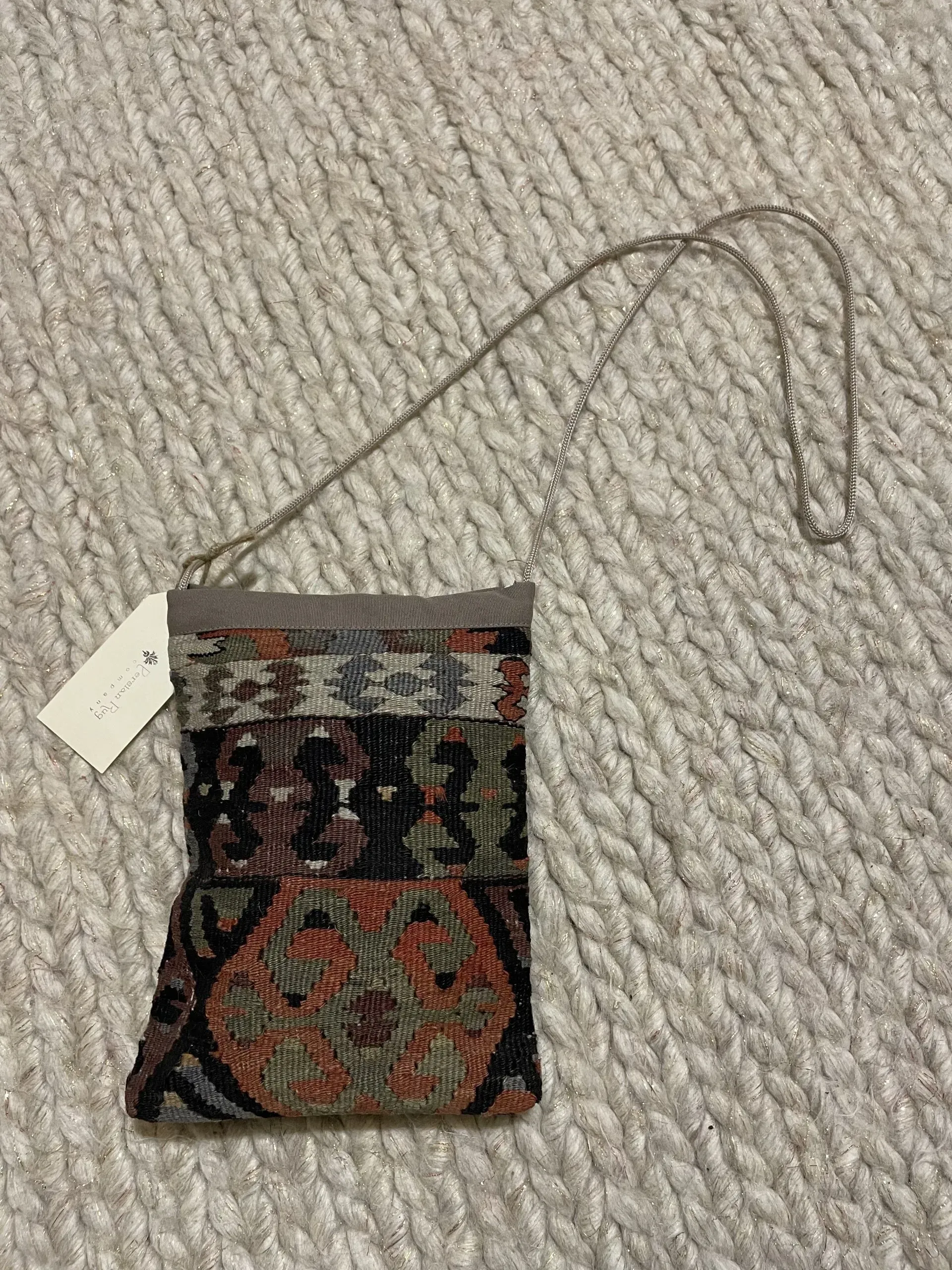 A small bag with a tag on it is sitting on a carpet.