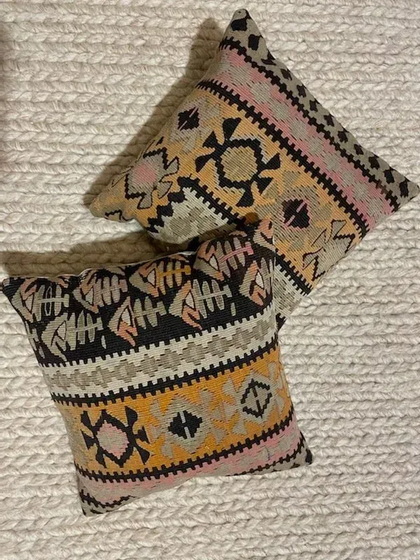 Two pillows are sitting on top of each other on a white blanket.