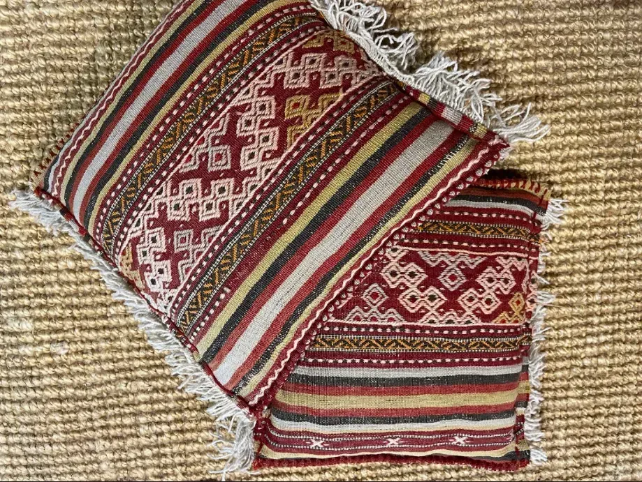 Two colorful pillows are sitting on top of a rug.