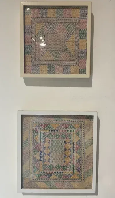 Two framed pictures are hanging on a white wall.
