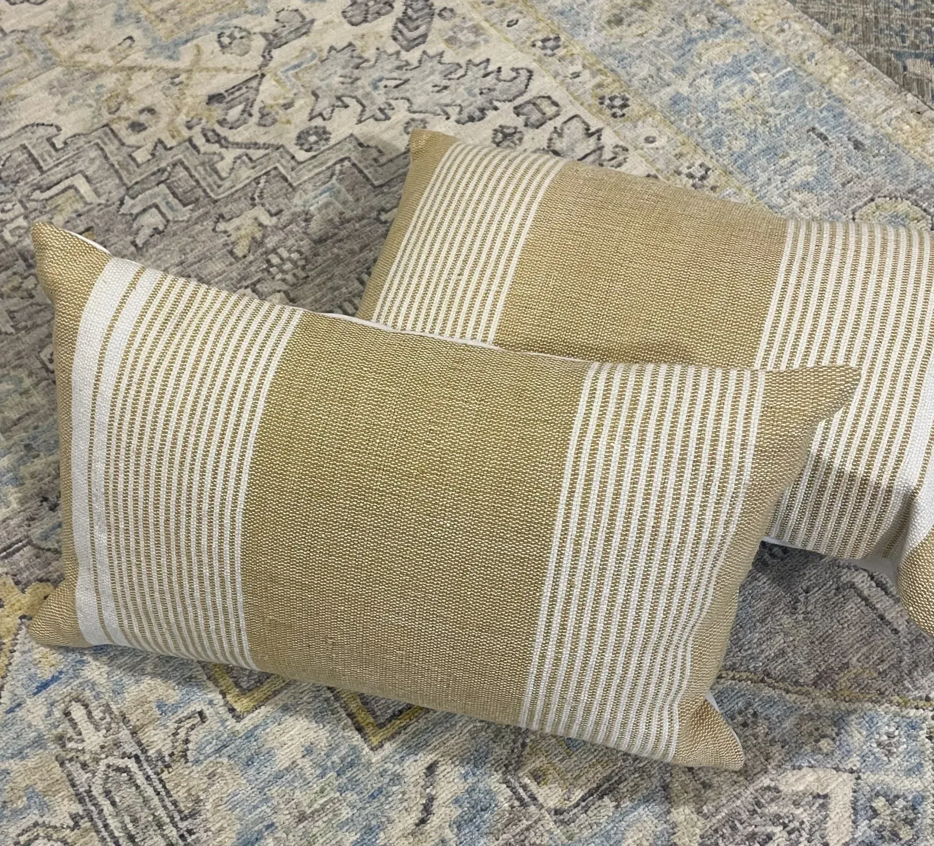 Two pillows are sitting on a rug on top of a rug.