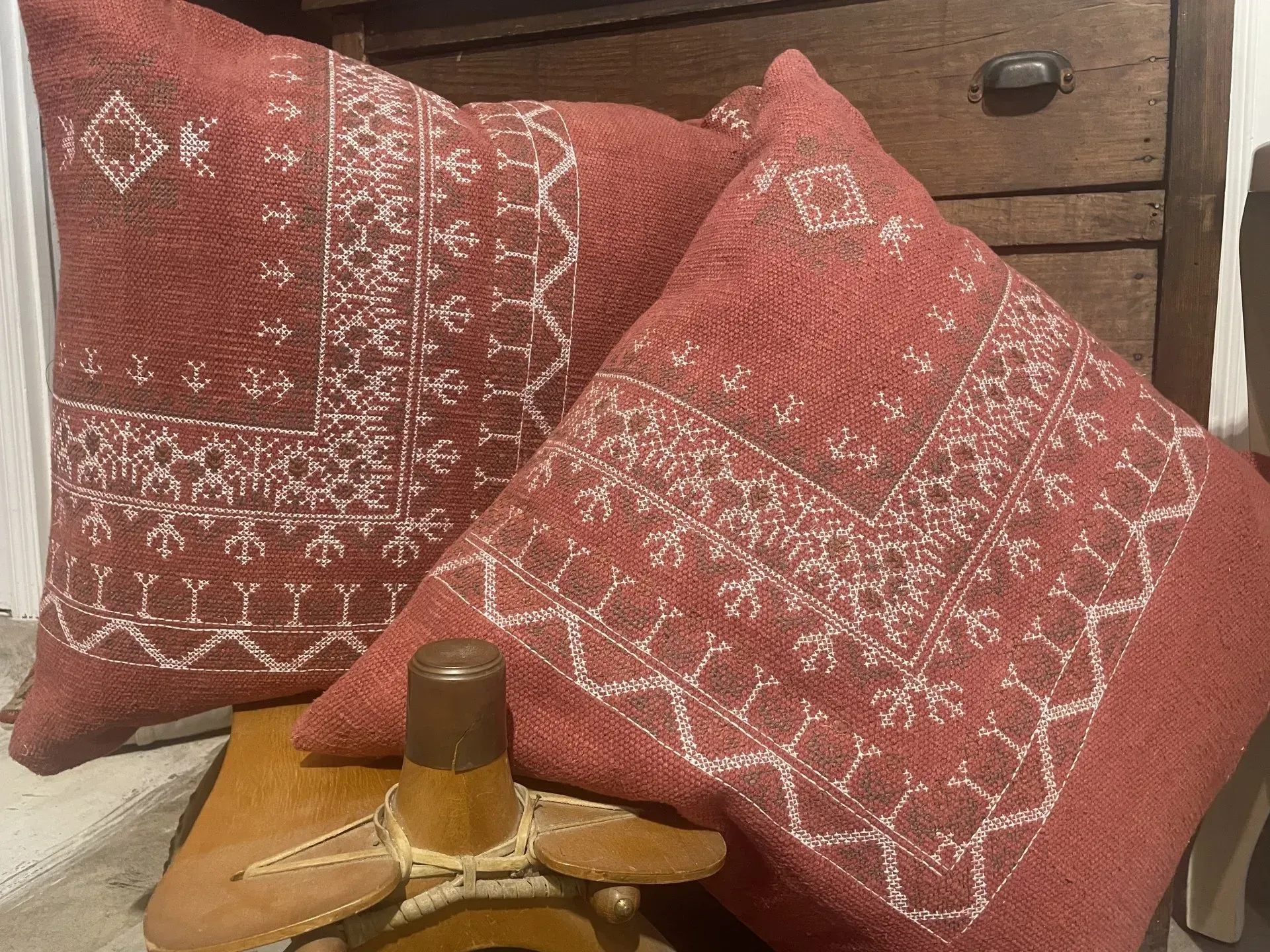 Two red pillows are sitting on top of a wooden dresser.