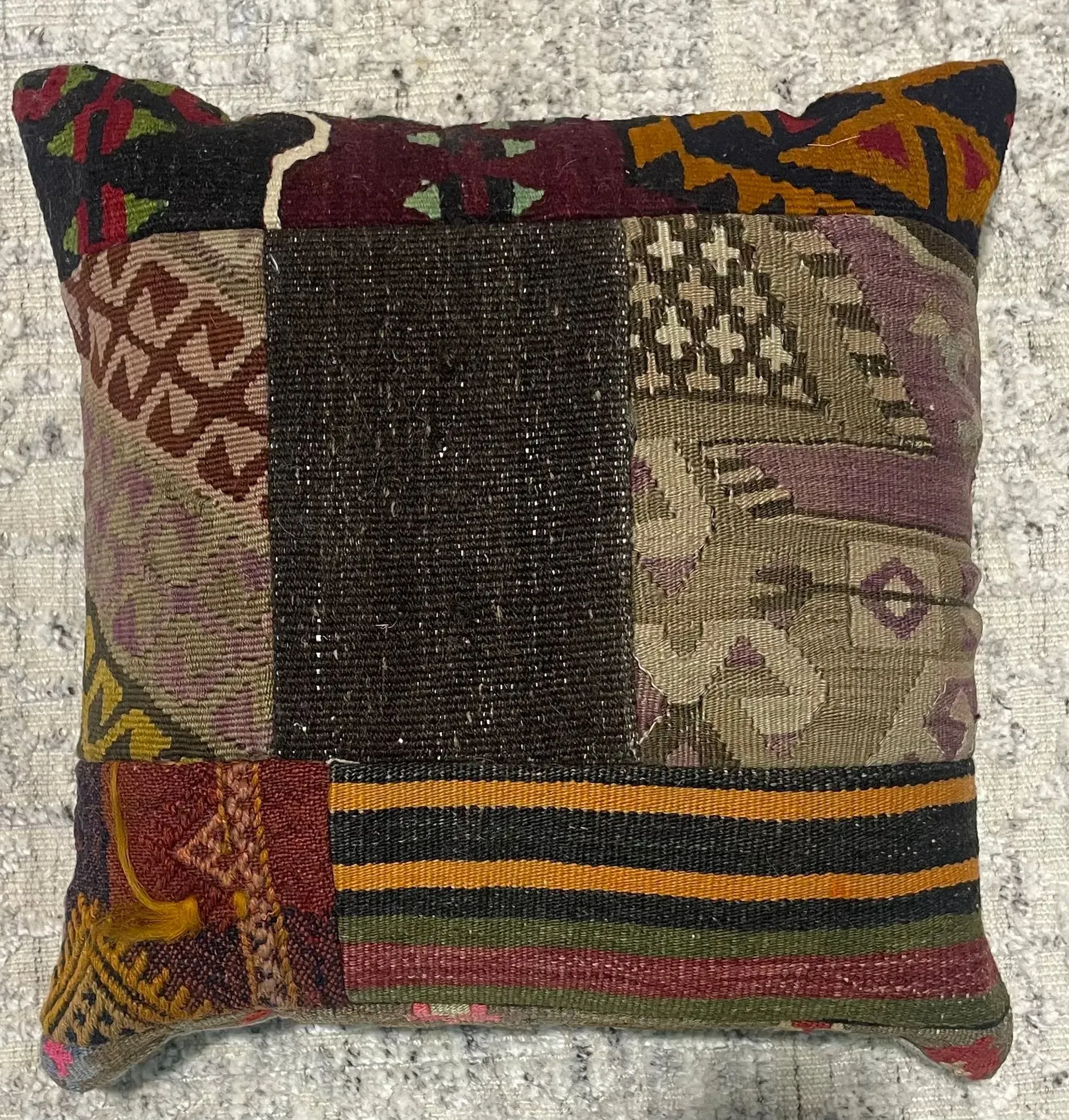 A colorful pillow is sitting on a carpet.