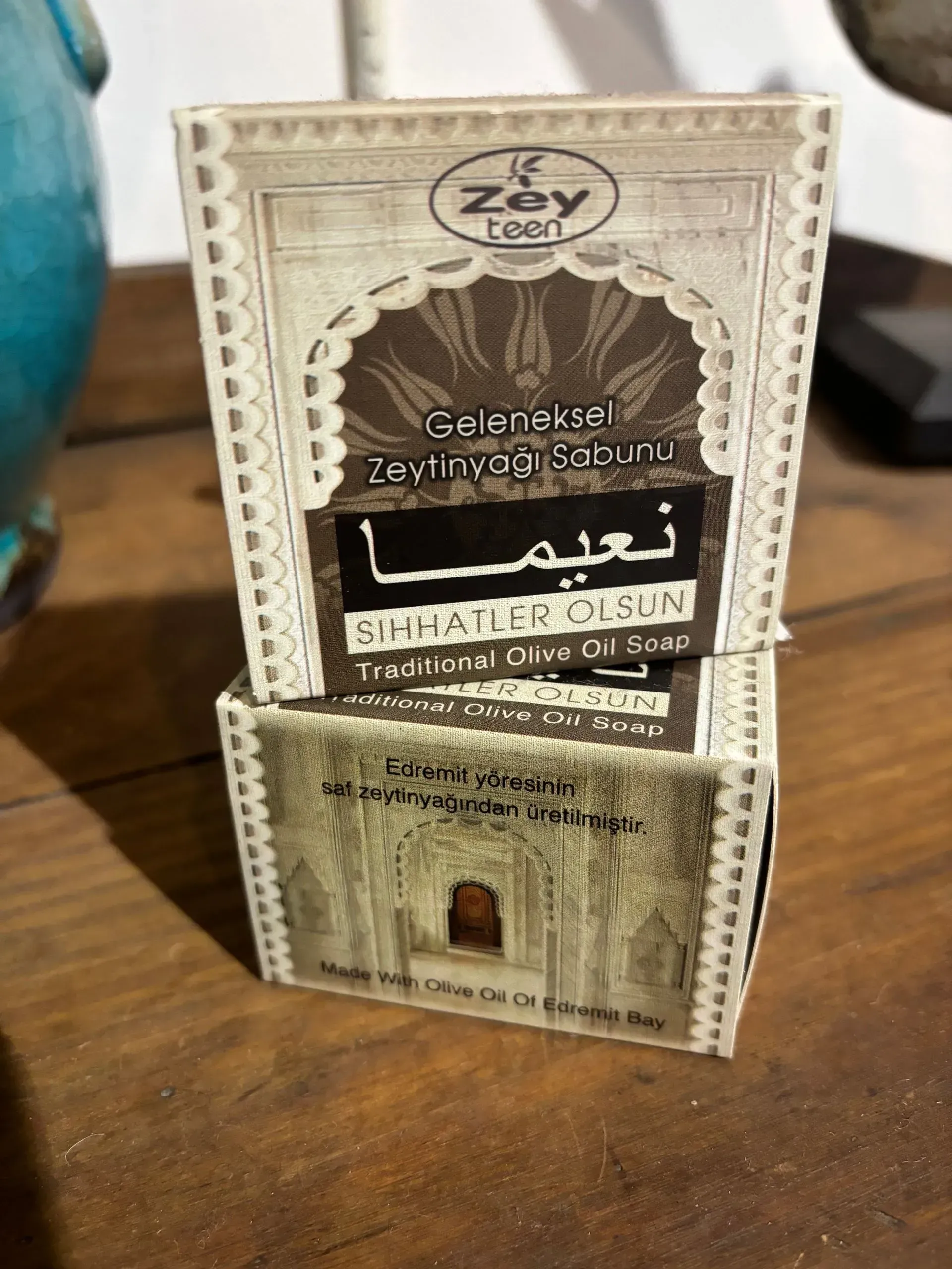 Two boxes of soap are stacked on top of each other on a wooden table.