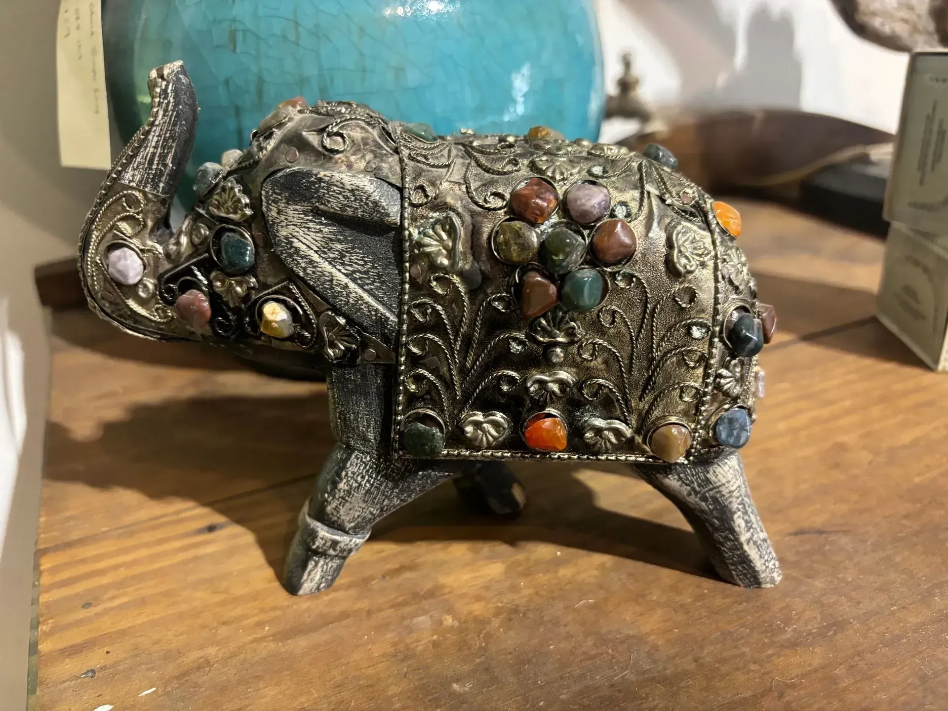 A statue of an elephant with a blue vase in the background.