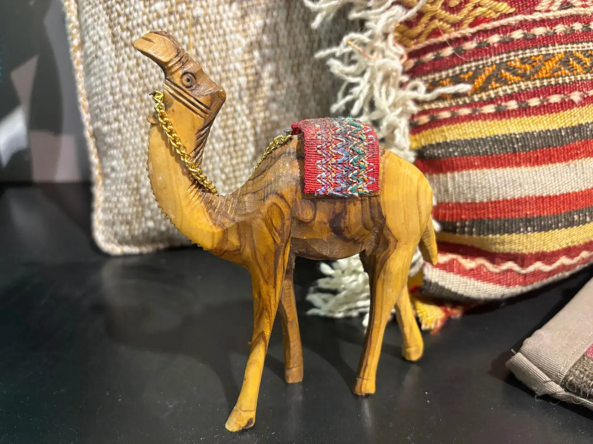 A small wooden camel figurine is sitting on a table.