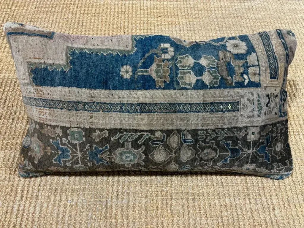 A pillow with a pattern on it is sitting on a rug.