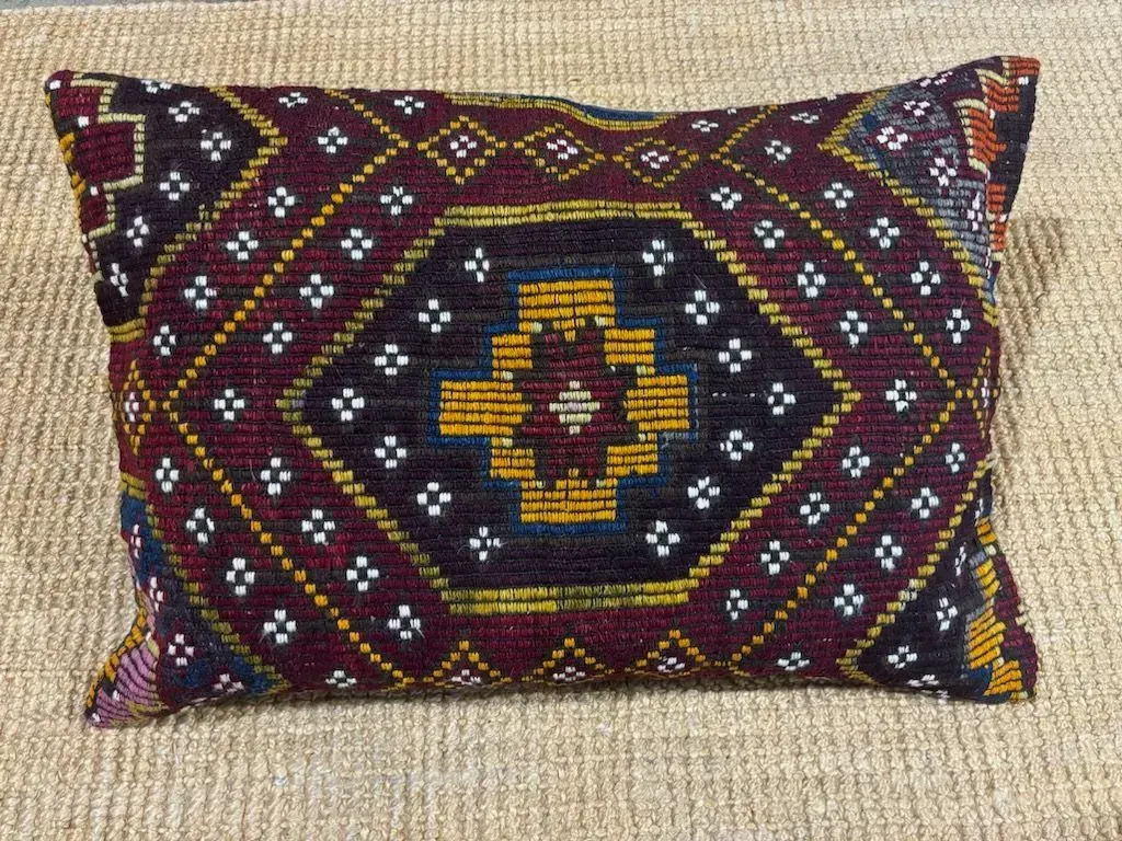 A pillow with a pattern on it is sitting on a rug.